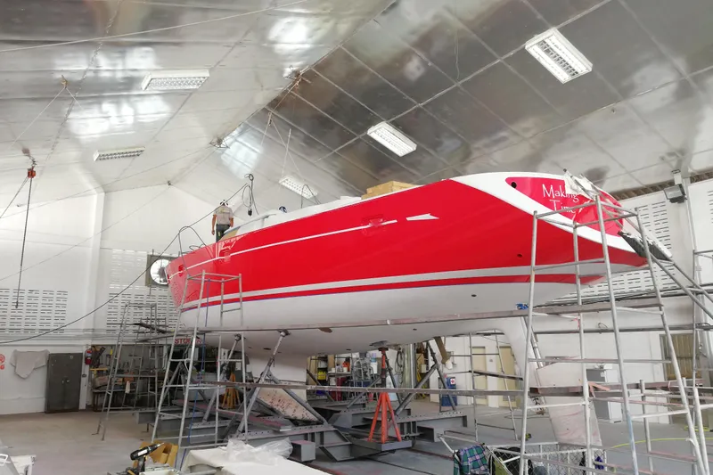 Making Time Yacht Photos Pics Red 2004 Oyster 53 yacht undergoing maintenance in a spacious indoor facility.