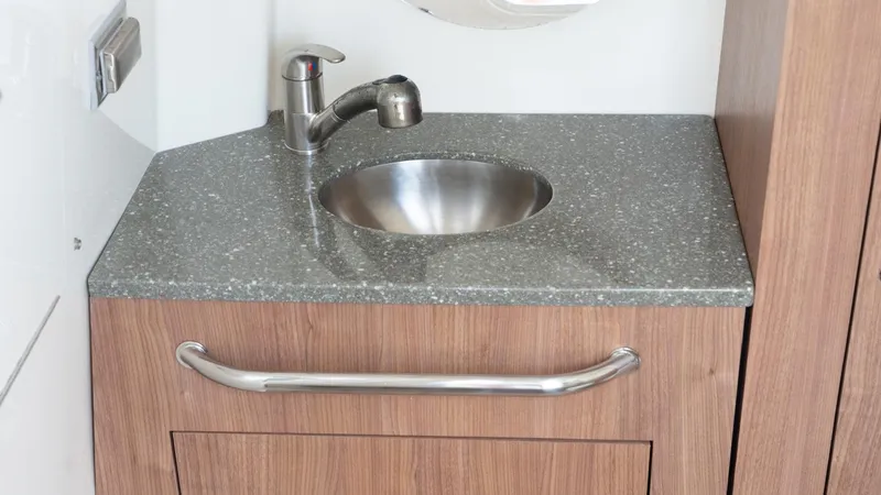  Yacht Photos Pics 2019 Boston Whaler 350 Outrage bathroom sink with modern faucet and wooden cabinetry.