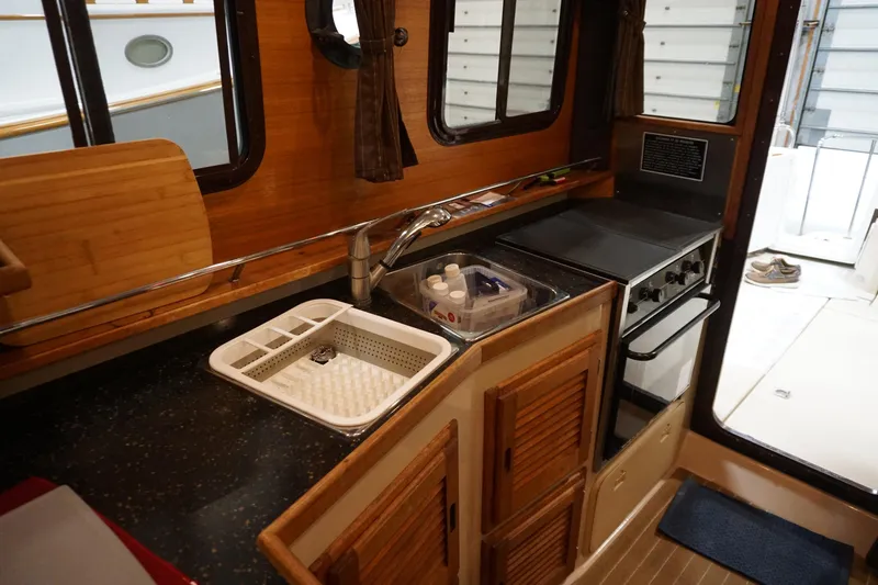  Yacht Photos Pics 2013 Ranger Tugs S-31 boat kitchen with sink, stove, and wooden cabinetry.