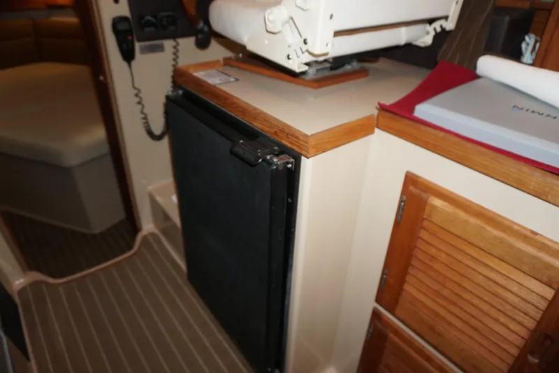  Yacht Photos Pics Interior of 2013 Ranger Tugs S-31 showing compact kitchen area with fridge and wooden cabinets.
