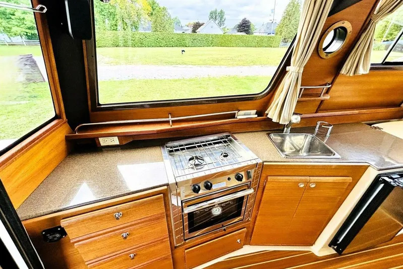  Yacht Photos Pics 2017 Ranger Tugs R-29S interior kitchen with stove, sink, and wooden cabinetry.