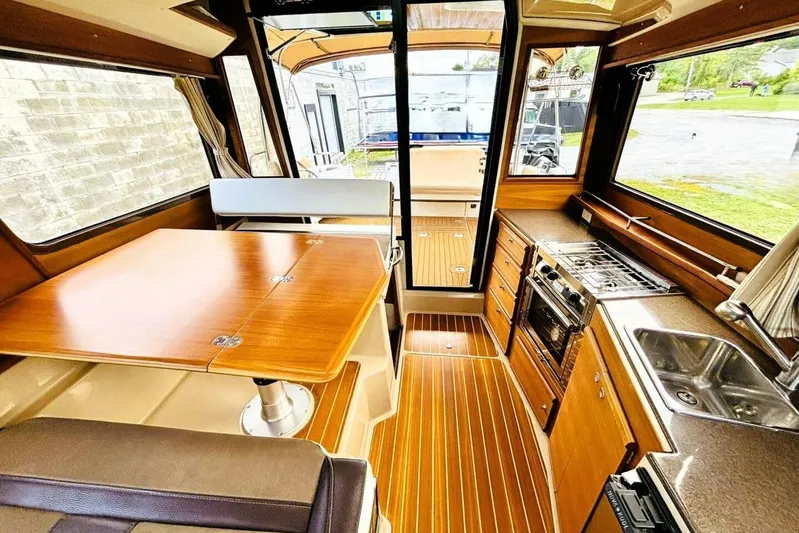  Yacht Photos Pics Interior of 2017 Ranger Tugs R-29S, featuring wood finishes, dining area, and compact kitchen.