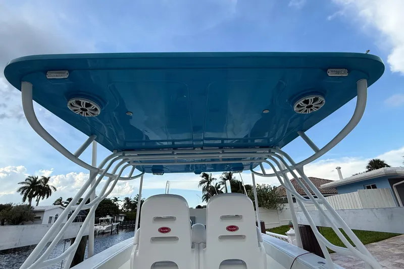  Yacht Photos Pics 2021 Marlin 39 CC boat with blue T-top and speakers, docked near palm trees.