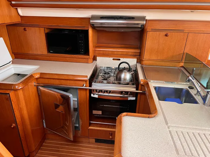 Jethro Yacht Photos Pics Luxurious 2003 Jeanneau Sun Odyssey 54 DS yacht kitchen with wood cabinetry and modern appliances.