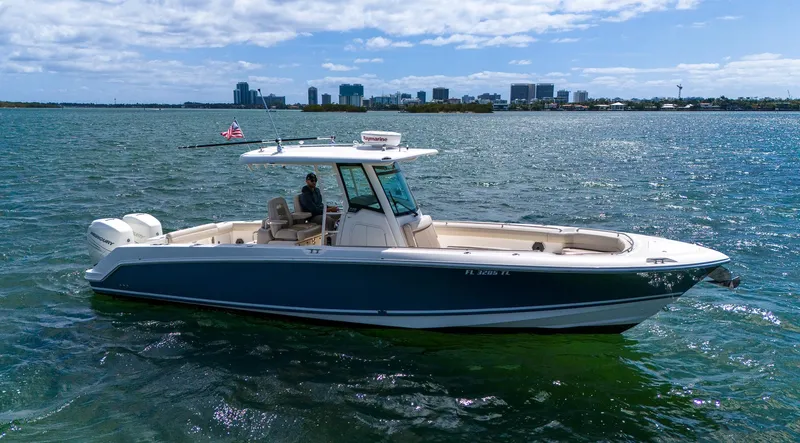 Rocco Yacht Photos Pics 2020 Boston Whaler 330 Outrage boat cruising on a sunny day with city skyline in the background.