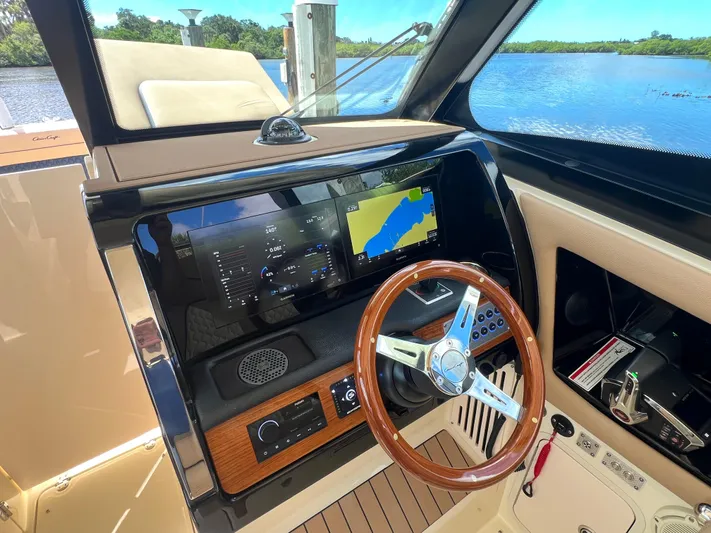  Yacht Photos Pics 2024 Chris-Craft Calypso 32 dashboard with navigation screen and wooden steering wheel.