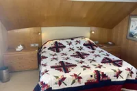 Cozy bedroom with a colorful quilted bedspread, wooden walls, and built-in nightstands.
