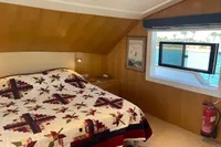 Cozy bedroom in 2024 Custom Canyon 92 yacht with quilted bedspread and ocean view.