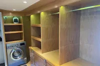 Modern laundry room with wooden shelves, washing machine, and ambient lighting in a Custom Canyon 92, 2024.