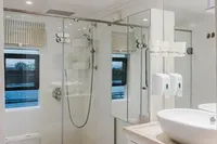 Modern bathroom in 2024 Custom Canyon 92 RV with shower, toilet, and sink.