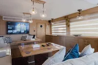 Luxurious yacht interior with modern decor, featuring a TV, wooden furnishings, and elegant lighting. Custom Canyon 92, 2024.