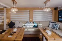 Luxurious yacht interior with wooden tables, plush cushions, and modern lighting, Custom Canyon 92, 2024.