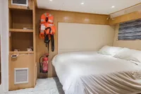 Cozy cabin interior of Custom Canyon 92 yacht, featuring a bed, life jackets, and fire extinguisher.