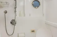 Compact bathroom with shower, toilet, and porthole in 2024 Custom Canyon 92 model.