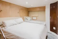 Luxurious bedroom interior in 2024 Custom Canyon 92 yacht, featuring twin beds and elegant wood paneling.