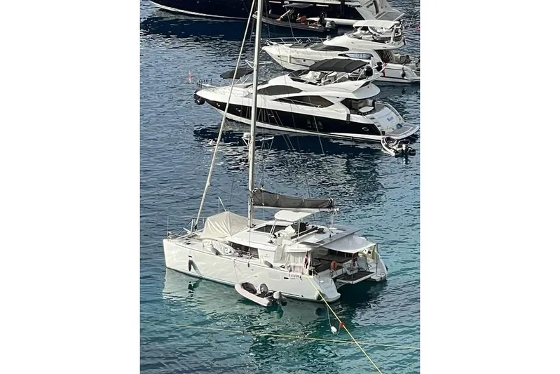  Yacht Photos Pics 2018 Lagoon 450 F catamaran anchored among luxury yachts in clear blue water.