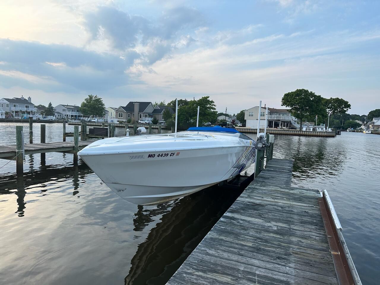 1997 Outerlimits 37 Stiletto boat docked at a marina with waterfront homes in the background.