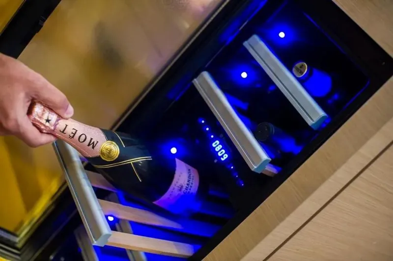  Yacht Photos Pics Hand placing Mo&euml;t champagne in illuminated wine cooler on Jeanneau 64 yacht, 2016 model.