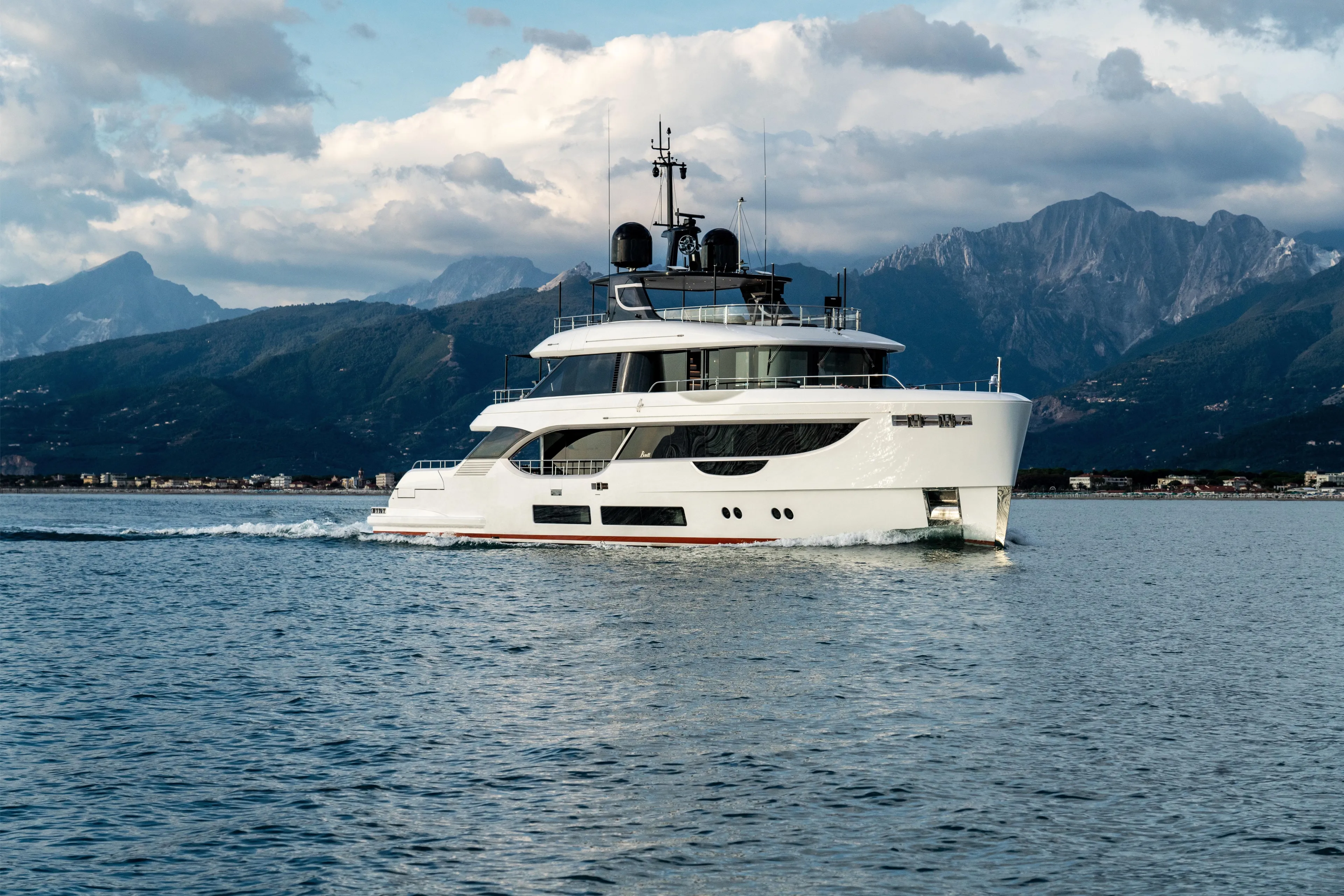 A+ Yacht Photos Pics Luxurious 2024 Benetti Oasis yacht cruising on serene waters with mountainous backdrop.