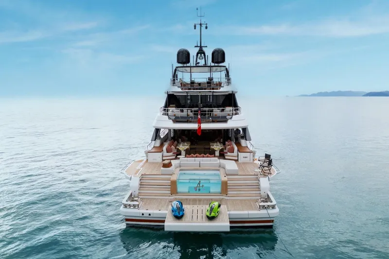 A+ Yacht Photos Pics Luxurious 2024 Benetti Oasis yacht with pool and jet skis on serene ocean.