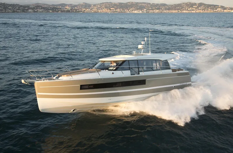  Yacht Photos Pics 2017 Jeanneau NC14 yacht cruising on open water with scenic coastline backdrop.