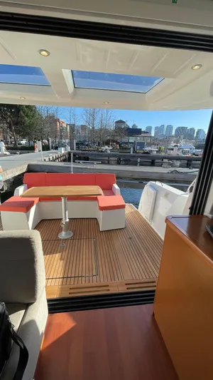  Yacht Photos Pics 2017 Jeanneau NC14 yacht with spacious deck, red seating, and city skyline view.