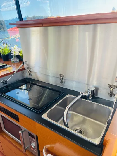  Yacht Photos Pics Modern kitchen area in a 2017 Jeanneau NC14 yacht with sink and stove.