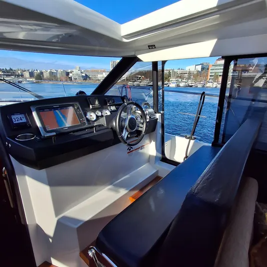  Yacht Photos Pics Interior view of 2017 Jeanneau NC14 boat cockpit with steering wheel and navigation system.