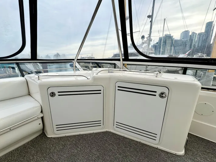 Slim Smitty Yacht Photos Pics 2002 Sea Ray 560 Sedan Bridge interior with white seating and storage, overlooking marina skyline.