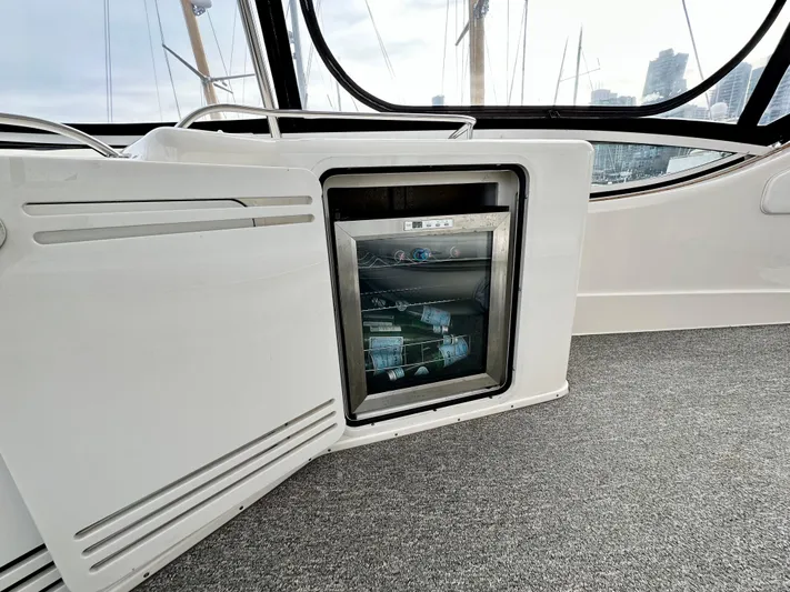 Slim Smitty Yacht Photos Pics 2002 Sea Ray 560 Sedan Bridge interior with mini fridge and open cabinet.