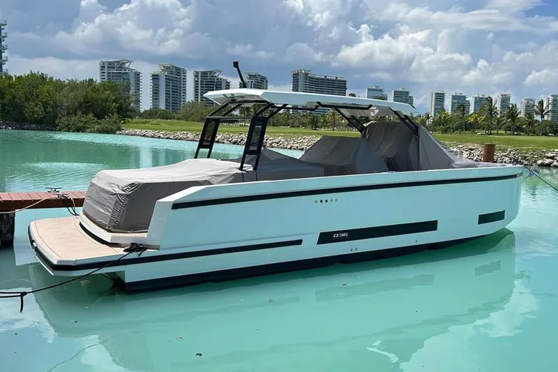 2025 Day 36 @ Cancun Yacht Photos Pics 2025 De Antonio Yachts D36 docked in a serene marina with modern buildings in the background.