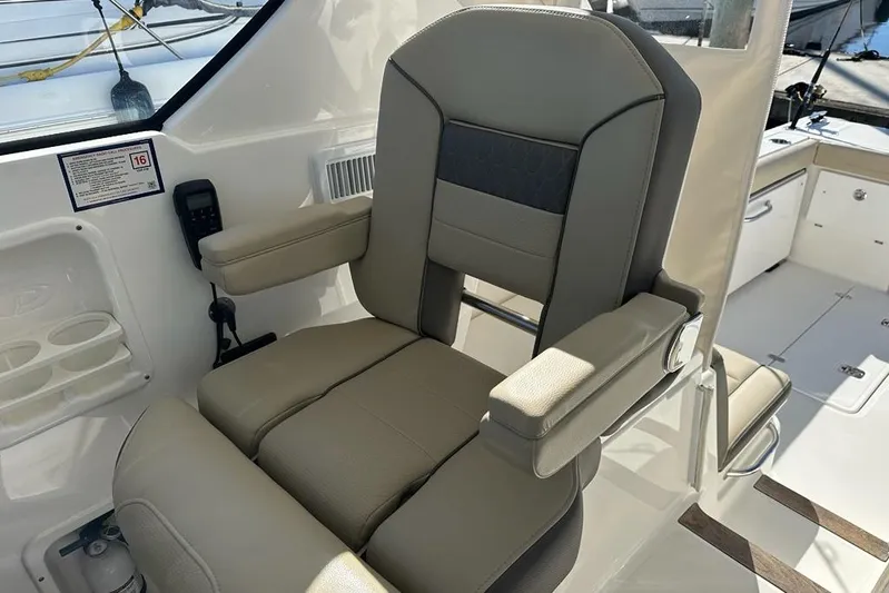 Wave Paver Yacht Photos Pics Captain's chair on 2020 Pursuit OS 355 Offshore boat, featuring beige upholstery and armrests.