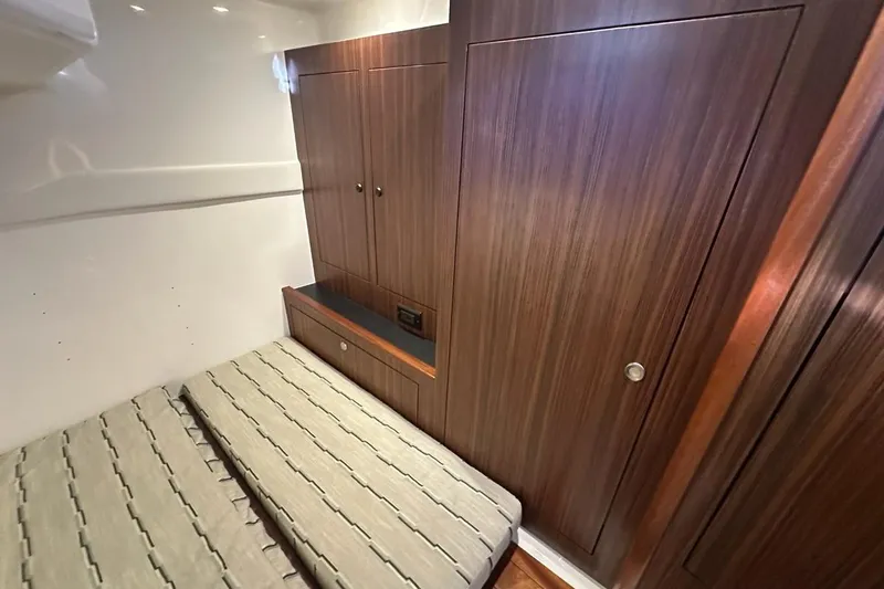 Wave Paver Yacht Photos Pics 2020 Pursuit OS 355 Offshore cabin interior with wood paneling and bed.