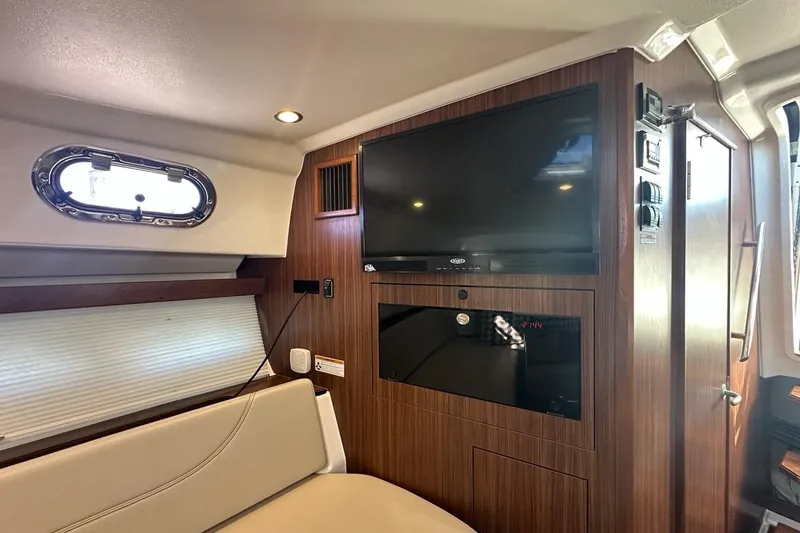 Wave Paver Yacht Photos Pics 2020 Pursuit OS 355 Offshore cabin interior with TV and wood paneling.