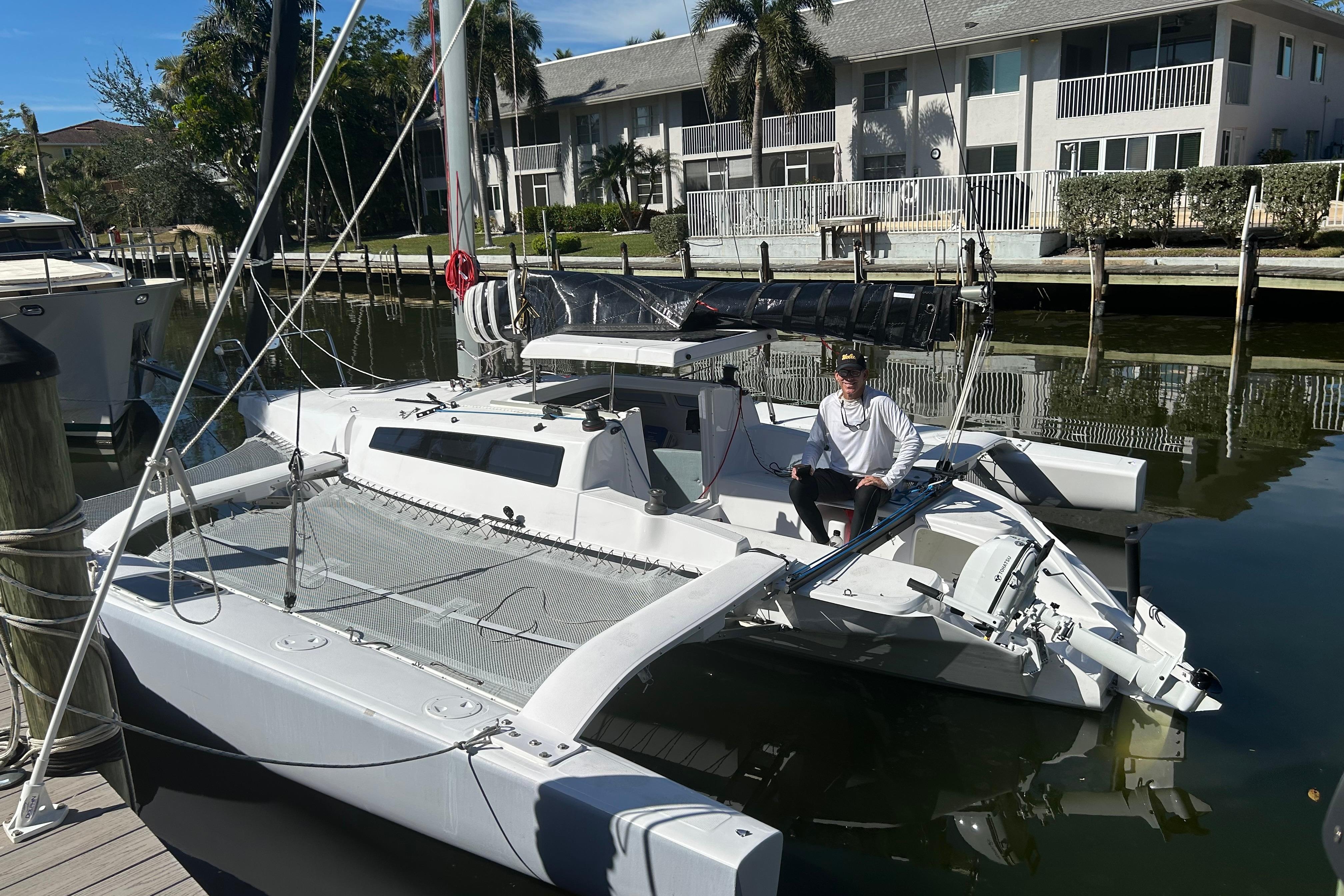 2025 Corsair 760 trimaran docked in a marina with a person onboard.