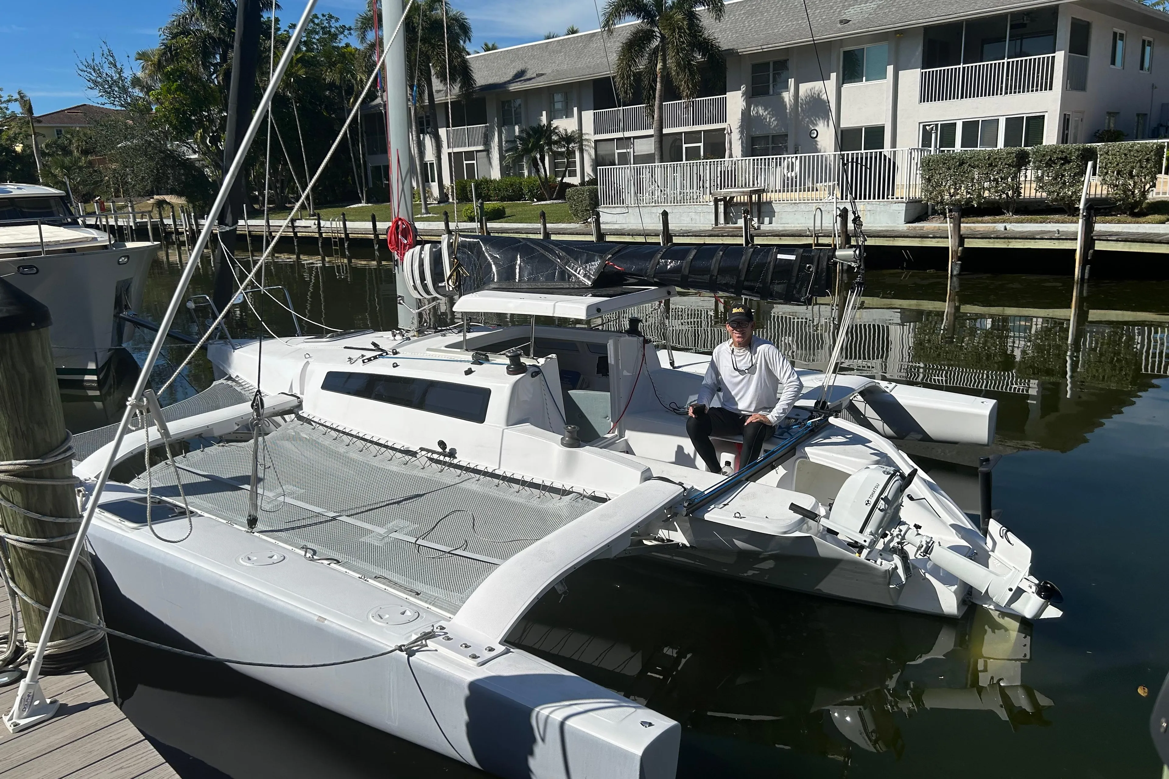 2025 Corsair 760 trimaran docked in a marina with a person onboard.
