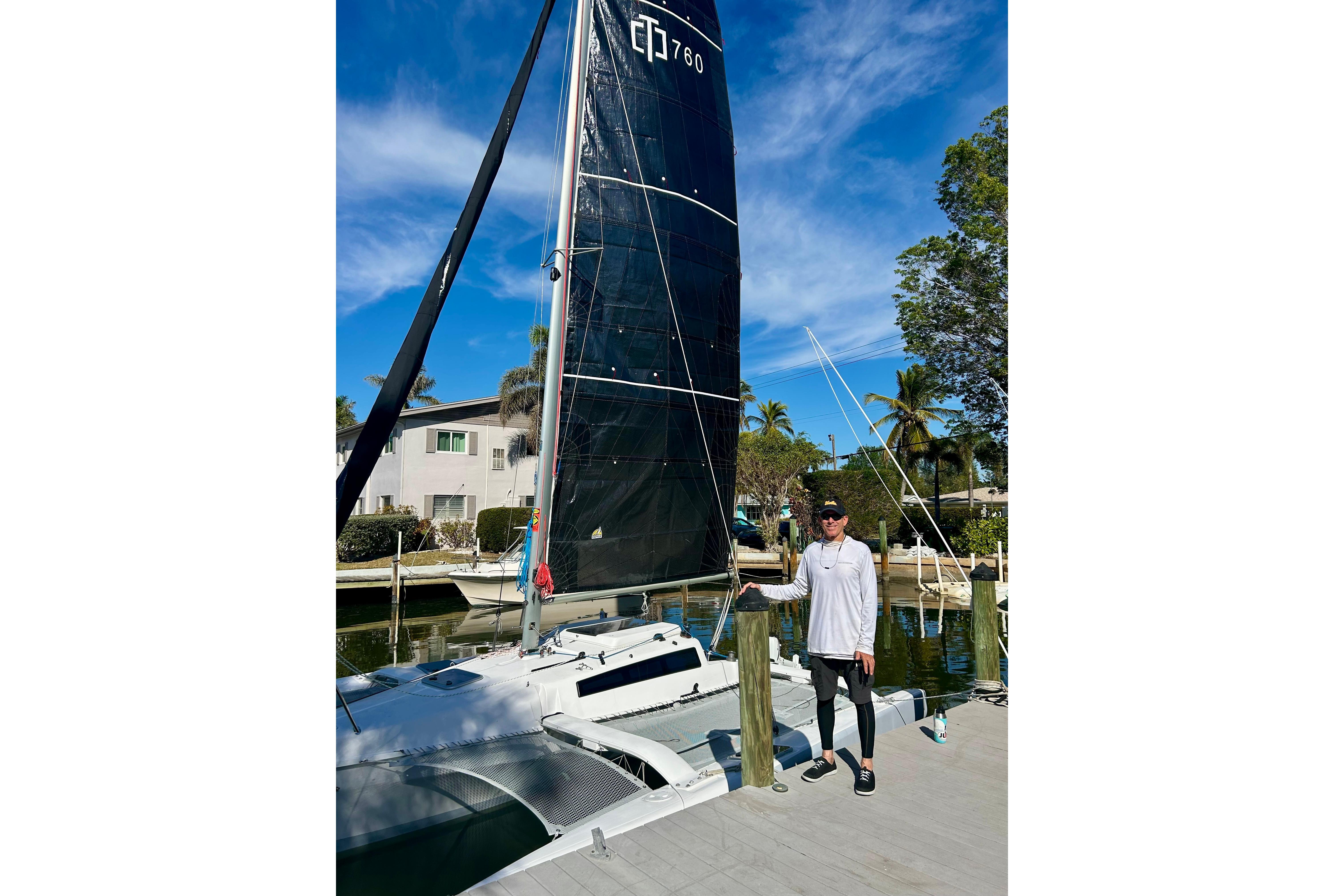 Man standing beside 2025 Corsair 760 sailboat at a sunny marina.