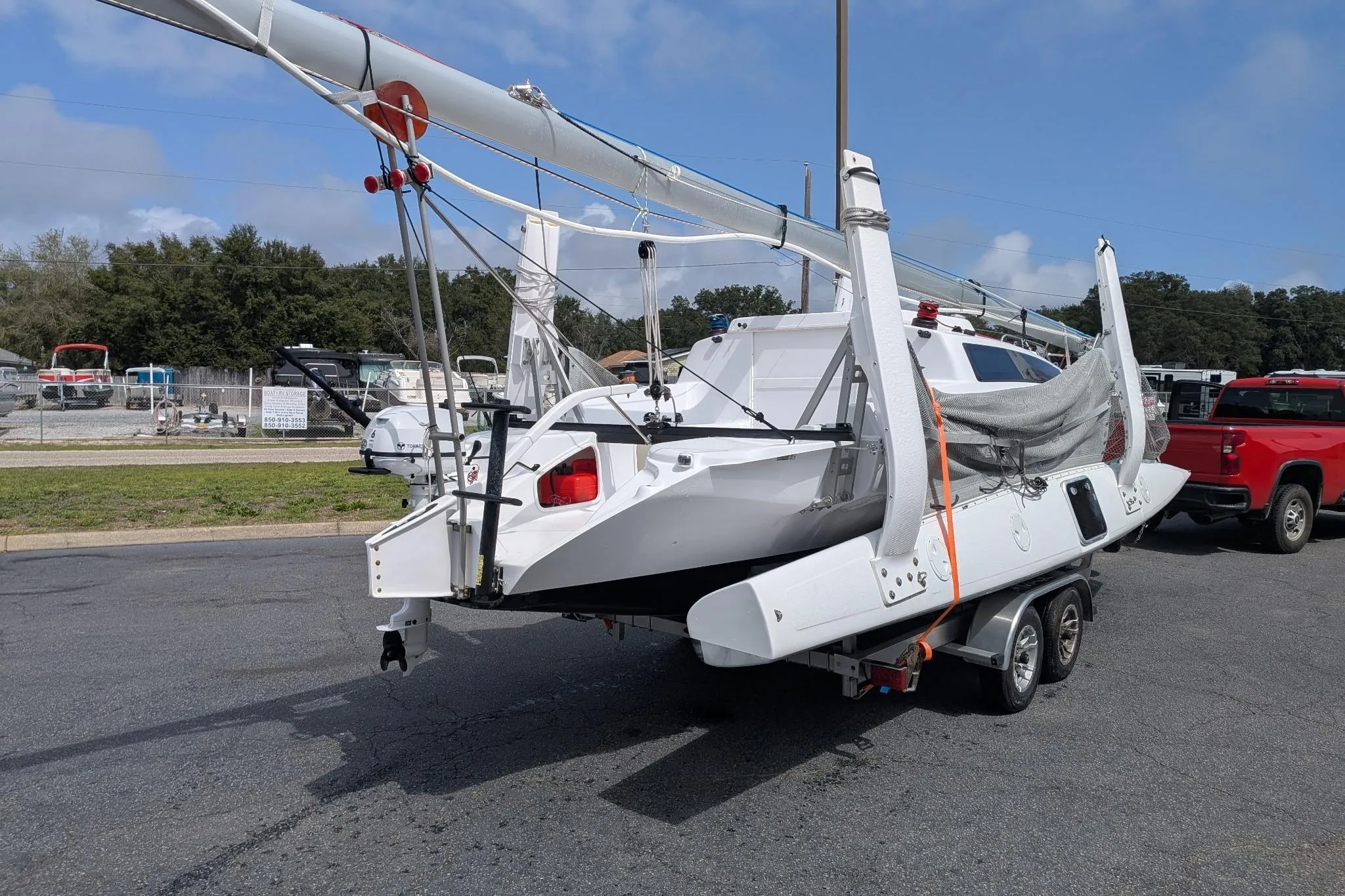 2025 Corsair 760 sailboat on trailer, parked outdoors under a clear sky.