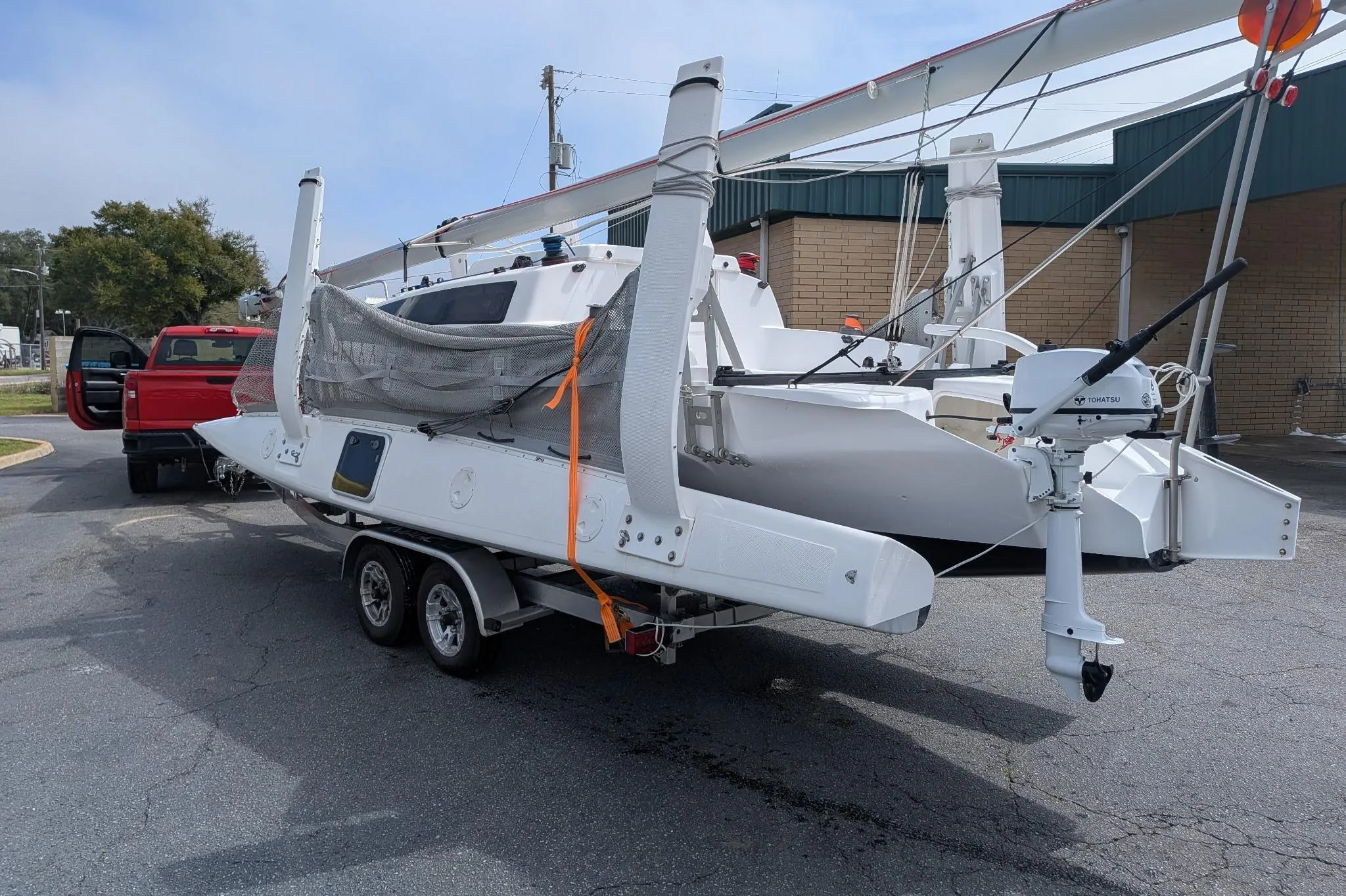 2025 Corsair 760 sailboat on trailer, parked near a red truck.