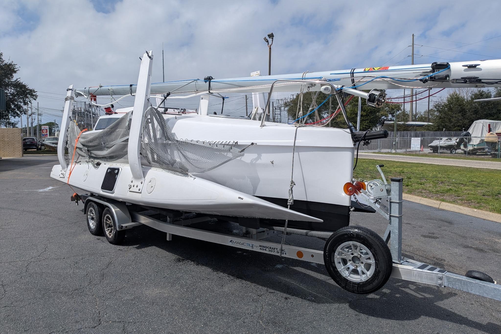 2025 Corsair 760 sailboat on trailer, parked outdoors under cloudy sky.