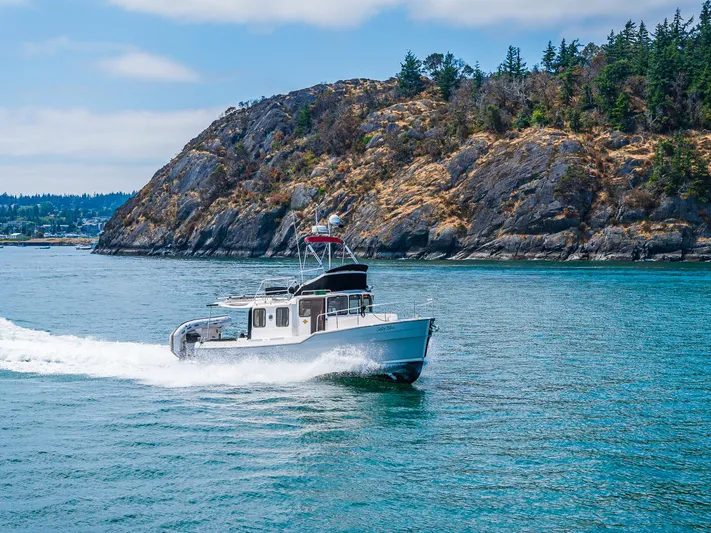 Salty Bliss Yacht Photos Pics 2021 Ranger Tugs R-31 CB cruising near rocky coastline under clear skies.