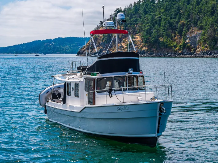 Salty Bliss Yacht Photos Pics 2021 Ranger Tugs R-31 CB boat cruising near a forested coastline.