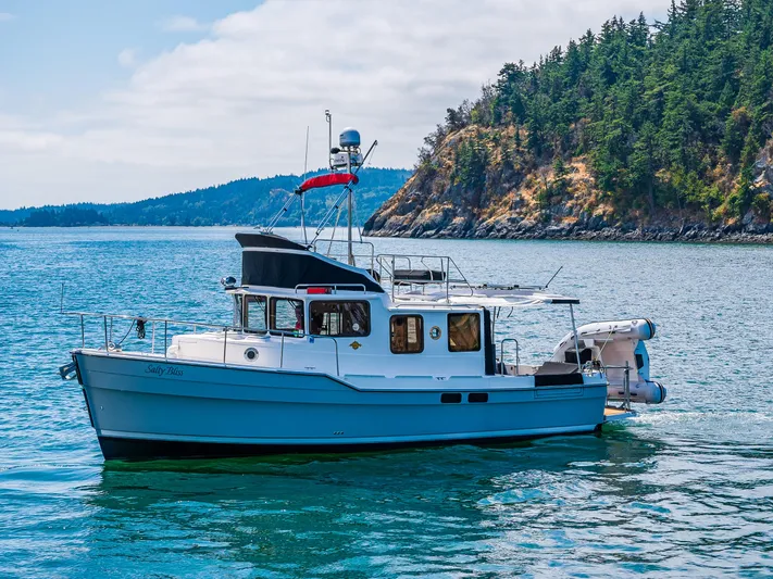 Salty Bliss Yacht Photos Pics 2021 Ranger Tugs R-31 CB cruising near a forested coastline.
