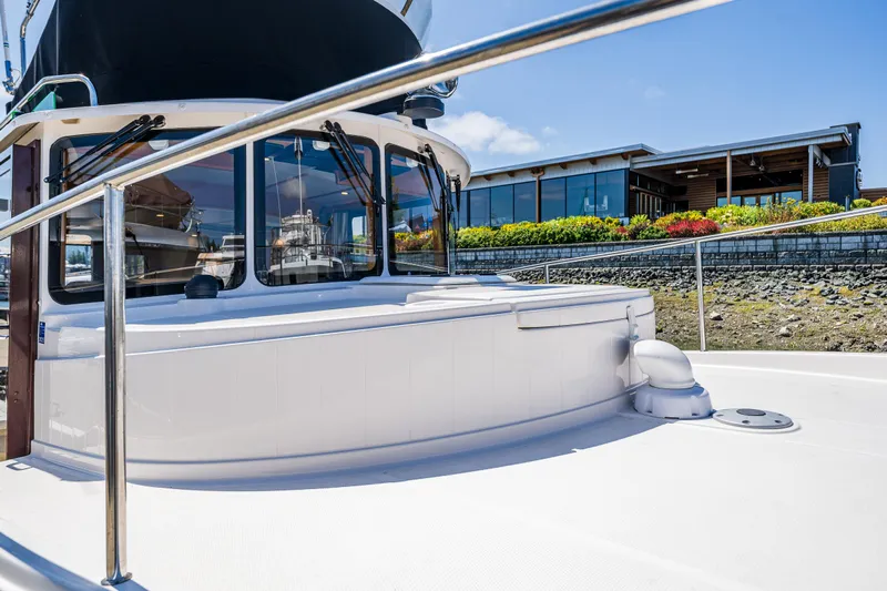 Salty Bliss Yacht Photos Pics 2021 Ranger Tugs R-31 CB boat docked near a modern building with landscaped surroundings.