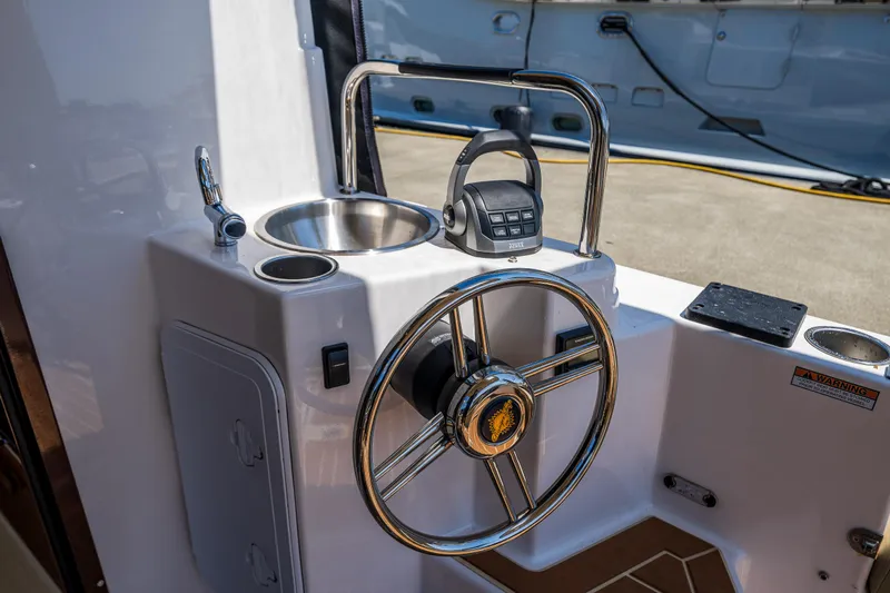 Salty Bliss Yacht Photos Pics 2021 Ranger Tugs R-31 CB helm with steering wheel, sink, and controls.
