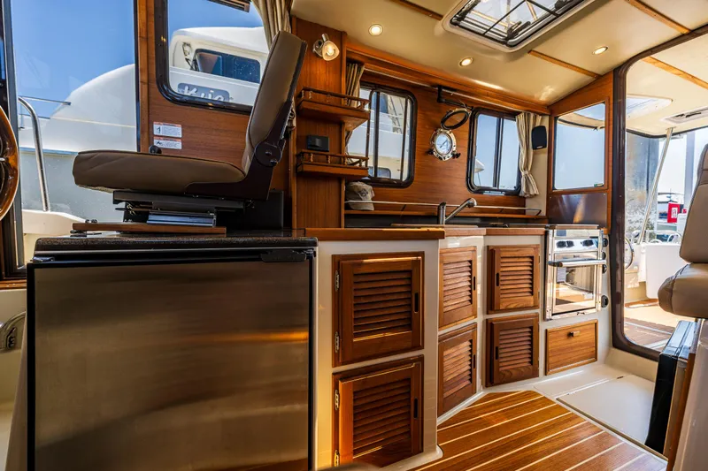 Salty Bliss Yacht Photos Pics Interior of 2021 Ranger Tugs R-31 CB, featuring wood cabinetry and modern appliances.