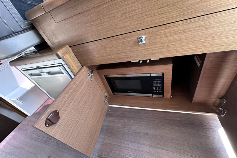 Pawsitive Attitude Yacht Photos Pics 2019 Jeanneau 895 interior kitchen with microwave and wooden cabinetry.