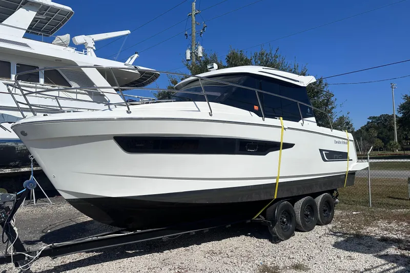 Pawsitive Attitude Yacht Photos Pics 2019 Jeanneau 895 boat on trailer, parked outdoors under clear blue sky.