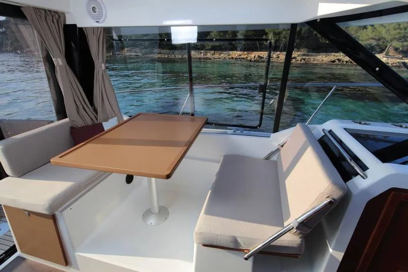 Pawsitive Attitude Yacht Photos Pics Interior of 2019 Jeanneau 895NC boat with seating and table, overlooking water.