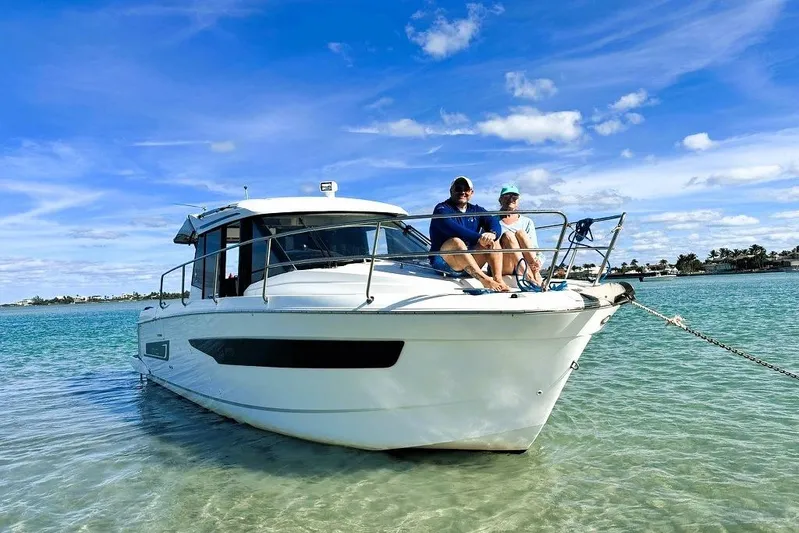 Pawsitive Attitude Yacht Photos Pics 2019 Jeanneau 895NC boat with two people relaxing on deck in clear blue water.